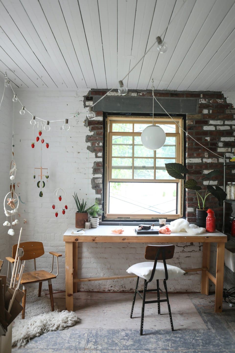 Schreibtisch mit Bastelmaterial und Pflanzen in einem rustikalen Atelier.